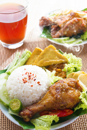 Popular Indonesian local food nasi ayam penyet, indonesian fried chicken rice. Fresh hot with steam smoke.の写真素材