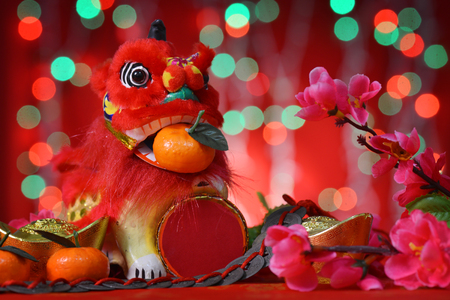 Chinese new year festival decorations, miniature dancing lion and mandarin orange, on glitter red background.の写真素材