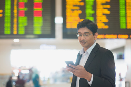 Asian Indian Business man checking on smartphone, doing online web check in at the airport .の写真素材