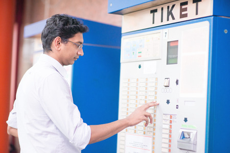 Asian Indian businessman buying transport ticket at vending machine.