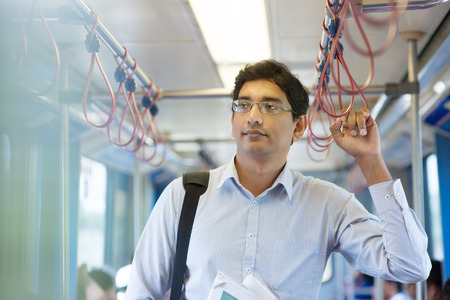 Asian Indian business man taking ride to work, standing inside train. Asian Indian business man taking ride to work, standing inside train.