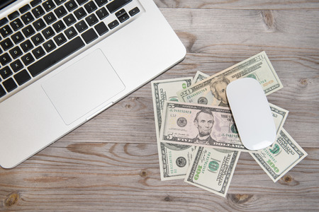 Top view laptop and bank notes on old wooden table.の写真素材