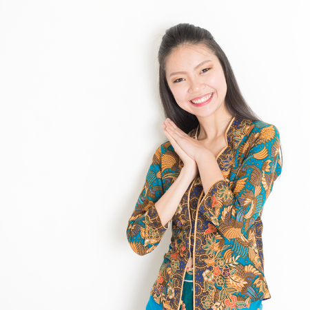 Portrait of happy Southeast Asian woman in batik dress on plain background.の写真素材