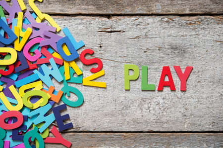 The colorful words "PLAY" made with wooden letters next to a pile of other letters over old wooden board.の写真素材