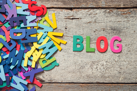 The colorful words "BLOG" made with wooden letters next to a pile of other letters over old wooden board.の写真素材