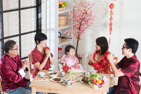   Happy Asian Chinese multi generation family with red cheongsam dining at home.の写真素材