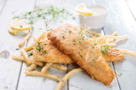 Fish and chips. Fried fish fillet with french fries on bright wooden background. Fresh cooked with hot smoke.の写真素材