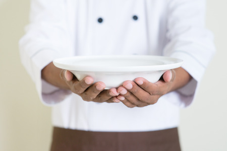 Black male chef in uniform presenting an empty dishの写真素材
