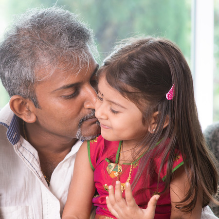 Happy Indian family at home. Asian dad kissing his toddler. Father and daughter indoor lifestyle.の写真素材