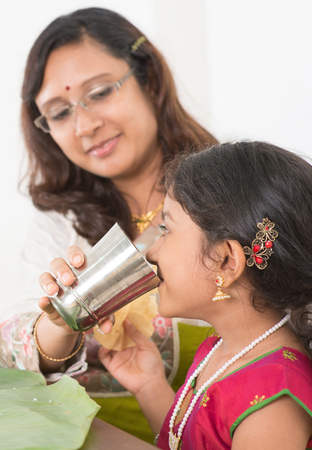 Indian family dining at home. Photo of child drinking water on dining table. Traditional home cook meal.の写真素材