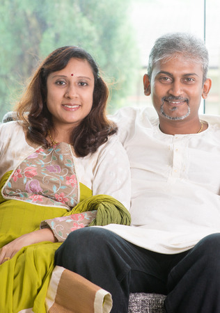 Indian couple. Portrait of mid age beautiful Indian family in traditional costume at home. Indian husband and wife indoor living lifestyle.の写真素材