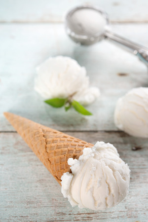 Scoop coconut ice cream in waffle cone with utensil on wood background.の写真素材