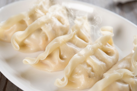 Close up fresh dumpling on plate with hot steams. Chinese food on old wooden background.の写真素材
