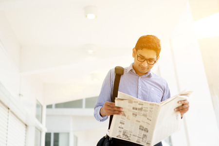 Asian Indian businessman reading newspaper on the way to work in a morning. Handsome male model.の写真素材