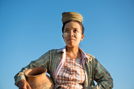 Portrait of mature Asian Burmese traditional female farmer carrying clay pot, Bagan, Myanmar