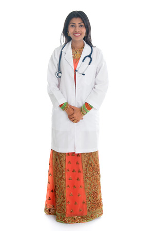 Full length Indian female medical doctor standing isolated on white background.の写真素材