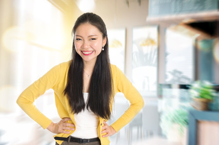 Happy young Asian businesswoman standing in her chain cafe. Female entrepreneur or shop owner.の写真素材