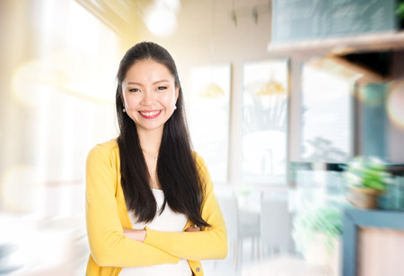 Asian female shop owner arms crossed standing in her cafe. Young woman entrepreneur.の写真素材