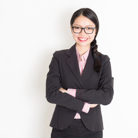 Portrait of Asian businesswoman in formalwear smiling and looking at camera, standing on plain background.の写真素材