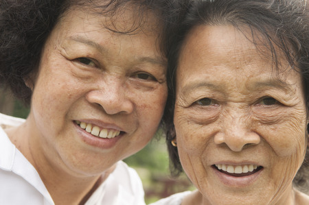 Portrait of healthy happy Asian seniors mother and daughter laughing at outdoor nature park, morning beautiful sunlight background.の写真素材