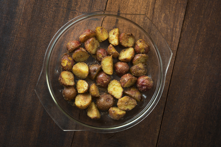 Top view freshly oven baked baby potatoes on wooden table, low light setting.の写真素材
