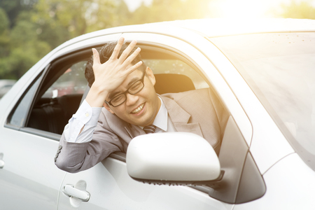 Portrait of pissed off  Asian business man driving car, hand banging his head in traffic jam. Negative human expression.の写真素材