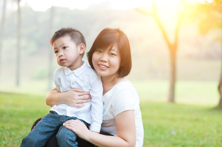 Mother hugging son in the park, Asian family outdoor lifestyle, morning with sun flare.の写真素材
