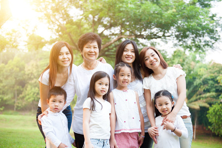 Group of happy Asian multi generations family portrait, grandparent, parent and children, outdoor nature park in morning with sun flare.の写真素材