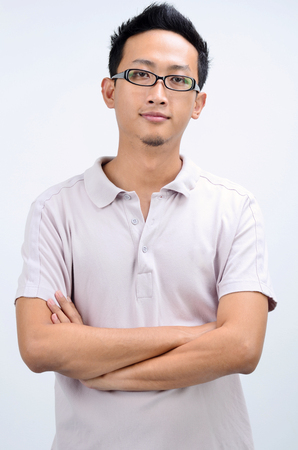 Portrait of cool Asian man arms crossed, standing isolated on plain background.の写真素材