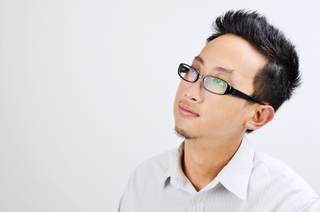 Portrait of Asian business man thinking and looking at side, standing isolated on plain background.の写真素材