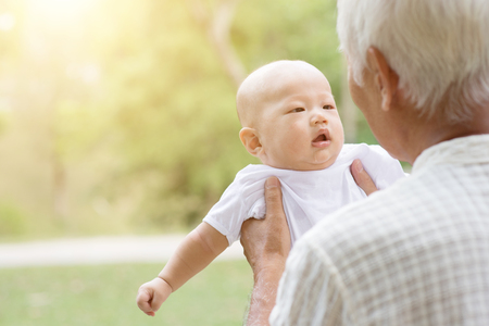 Happy grandfather with baby grandson at outdoors park. Asian family, life insurance concept.の写真素材
