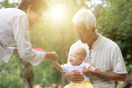 Baby grandson and grandparents having fun outdoors. Asian family, life insurance concept.の写真素材
