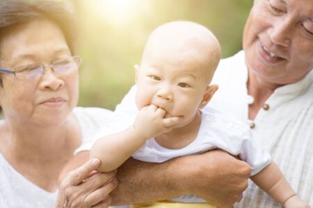 Senior couple with baby grandchild, Asian grandparents family, life insurance concept.の写真素材