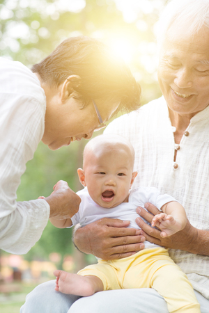 Happy grandparents with grandchild at outdoors park. Asian family, life insurance concept.の写真素材