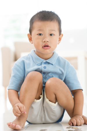 Asian young boy saving coins at home. Child future educational fund concept. の写真素材