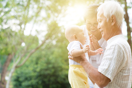 Grandparents holding baby grandson at outdoor park, Asian family, life insurance concept.の写真素材