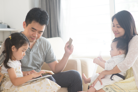 Online shopping with tablet pc and credit card. Happy Asian family at home, natural living lifestyle indoors.の写真素材