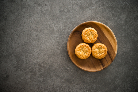 Traditional baked mooncakes is offered to friends or family during Mid-Autumn Festival. Flatlay table top view dark background with copy space. The Chinese character on the moon cake represent "lotus paste" in English.の写真素材