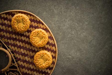 Traditional pastry moon cakes is offered to friends or family during Mid-Autumn Festival. Flatlay on table, top down view dark light with copy space. The Chinese character on the mooncake represent "lotus paste" in English.の写真素材