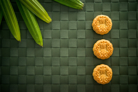 Traditional pastry moon cakes is eaten during the Mid-Autumn Festival. Flatlay table top view dark light with copy space. The Chinese character on the mooncake represent "lotus paste" in English.の写真素材