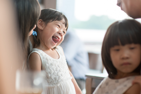 Candid shoot of people in cafeteria. Little girl with various face expression. Asian family outdoor lifestyle with natural light.の写真素材
