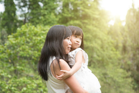 Asian family outdoors portrait. Mother and daughter at garden park.の写真素材