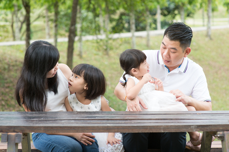 Asian family. Parents and children bonding at outdoor park. Empty space on wooden table.の写真素材