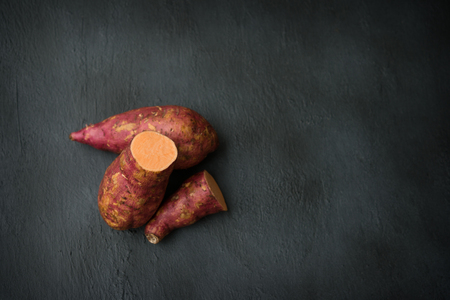 Raw orange sweet potatoes on wooden surface. Top view with copy space.の写真素材