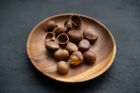 Chestnuts on wooden plate on darkの写真素材