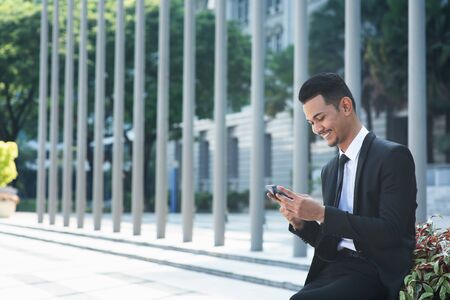 Businessman using mobile phone outdoor during office hour.の写真素材
