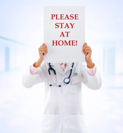 Medical staff holding a card with stay at home on it.の写真素材