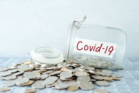 Coins in glass money jar with covid19 label, financial concept.の写真素材