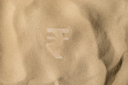 Indian Rupee Symbol or Sign Covered with Sand in the Sun after Crisisの写真素材