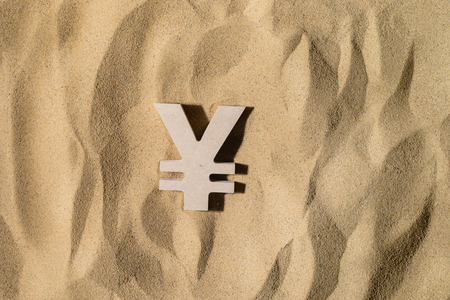 Japanese Yen or Chinese Yuan Symbol lies on the Sand in Direct Sunlightの写真素材